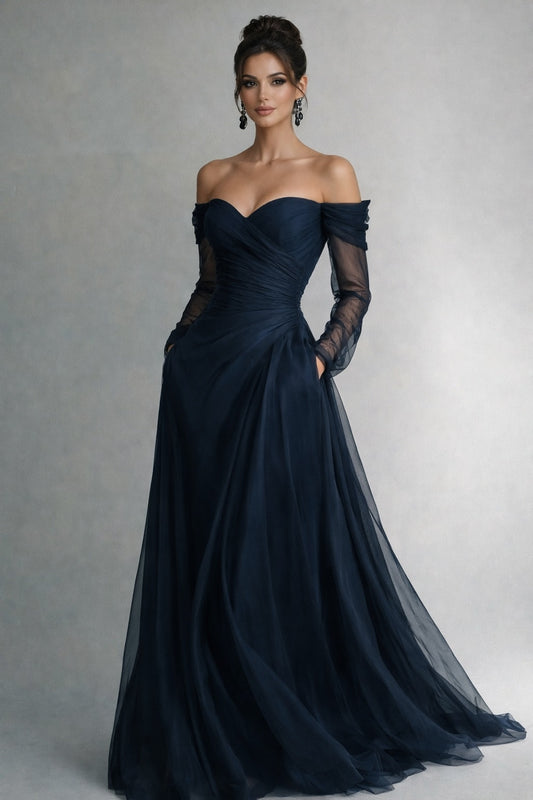 Woman wearing a dark blue off-shoulder gown with sheer sleeves against a neutral background
