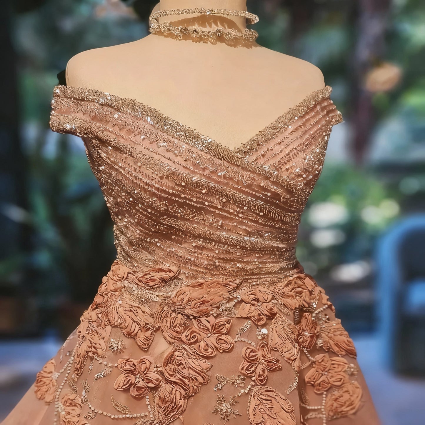 Elaborately designed off-shoulder dress with floral and bead details on a blurred background