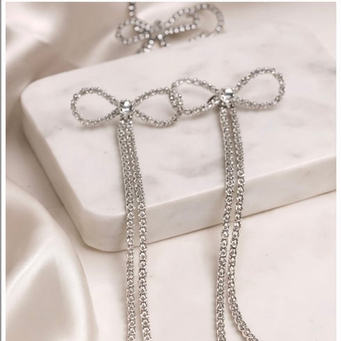 Silver chain earrings on a white satin surface