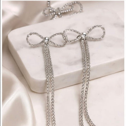 Silver chain earrings on a white satin surface