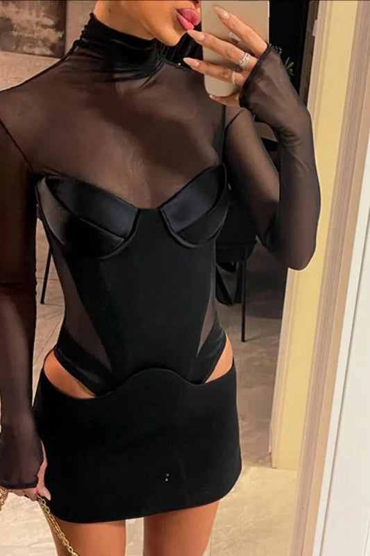 Person wearing a black and sheer dress with cut-out design, holding a phone.