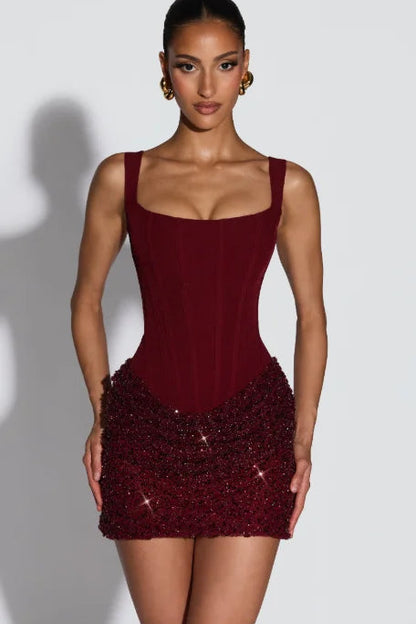 Woman wearing a burgundy dress with beaded hem on a white background