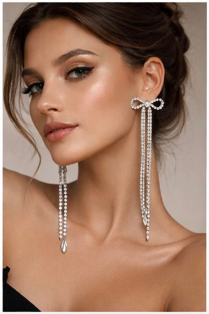 Woman wearing elegant earrings with dangling beads against a neutral background